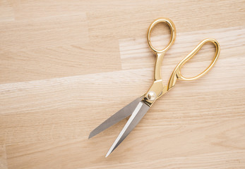 Gold colored scissors on a wooden table. Equipment used for sewing or tailoring work.