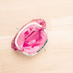 Elegant red purse lying on wooden table. The wallet is open and empty. Concept of luxury accessory, shopping and poverty.