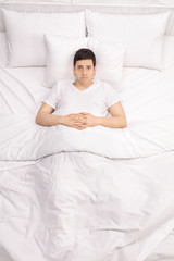 Worried young man laying in bed