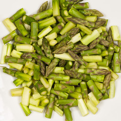 Close up on sliced pieces of green asparagus on a white plate