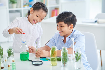 Girl adding liquid in test-tube with plant leaves