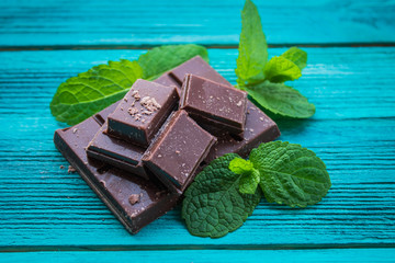 Slices of chocolate with mint on a wooden background