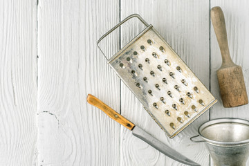 Grater, plunger , strainer and knife on the white wooden table top view