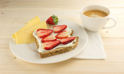 Coffee, cheese, bread with strawberry for breakfast on table