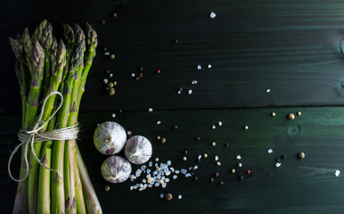 Green asparagus with garlic, salt and pepper mix on dark backgro