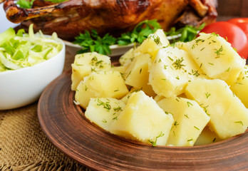Boiled potatoes in a clay bowl close-up and roasted goose