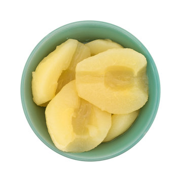 Full bowl of pears halves on a white background top view