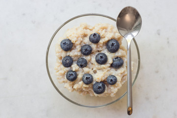 Bowl of oatmeal porridge with blueberry on marble table