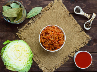 Braised cabbage with spices in a tomato sauce in a white bowl. The top view.