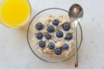 Bowl of oatmeal porridge with blueberry on marble table
