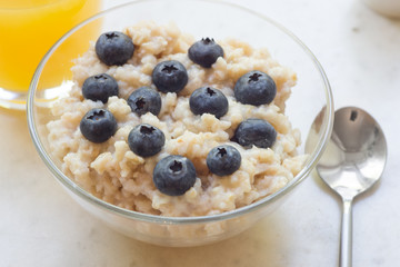 Bowl of oatmeal porridge with blueberry on marble table