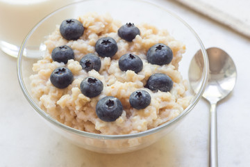 Bowl of oatmeal porridge with blueberry on marble table