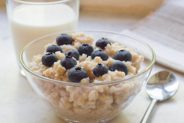 Bowl of oatmeal porridge with blueberry on marble table