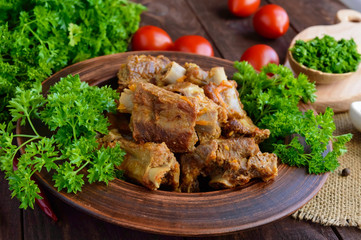 Pork ribs steamed with carrots, parsley decorated in a clay bowl on a wooden background. Close up