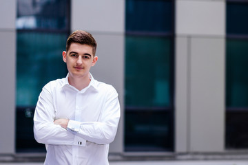 Portrait of handsome confident young businessman standing arms crossed, smiling happy, looking at camera