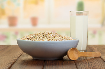 Bowl  oatmeal,  glass  milk, wooden spoon on  background of  kitchen.