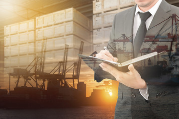 Businessman writing notebook with blurred cargo in wooden case and transportation port background trading export abroad concept