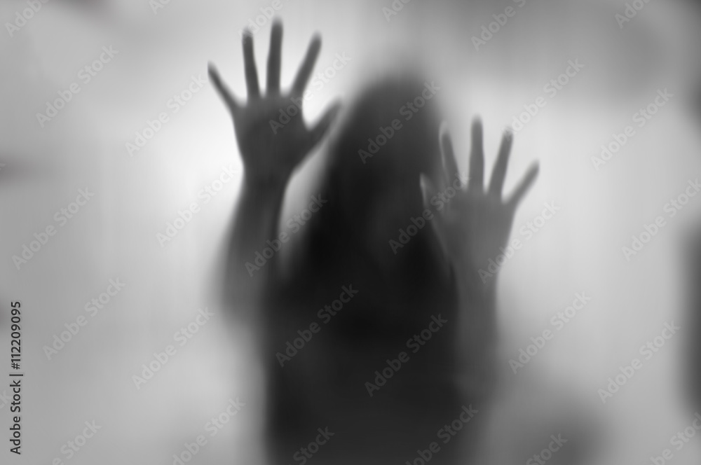 Wall mural Horror woman behind the matte glass in black and white. Blurry hand and body figure abstraction