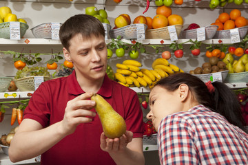 Assistant helping customer at vegetable counter of shop