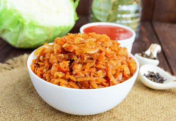 Braised cabbage with spices in a tomato sauce in a white bowl. Close-up.