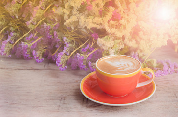 Cup of coffee behind beauty flower on wood background - Vintage