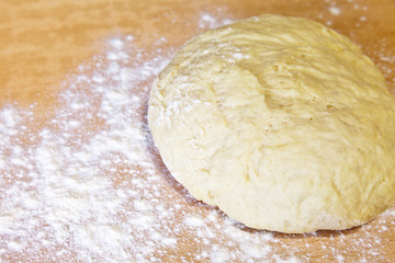 Pastry and wheat flour on a cutting board in the kitchen. Fresh yeast dough for homemade buns
