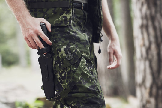 close up of soldier or hunter with knife in forest