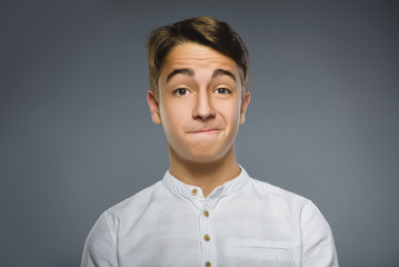 doubt, expression and people concept - boy thinking over gray background