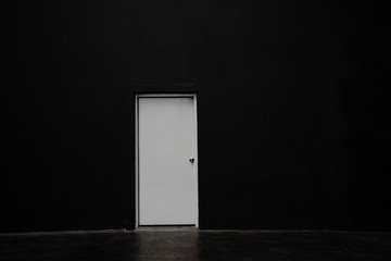 Black empty wall with white door