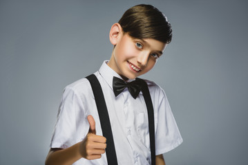 Happy boy. Closeup Portrait of handsome teenager smiling and show thumb up over grey background