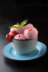 Strawberry ice cream with a sprig of mint in a cup