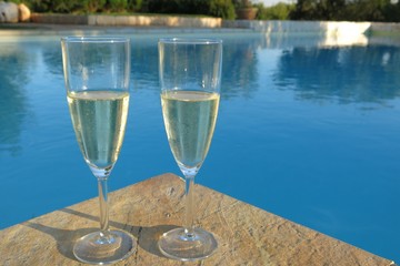 two champagne flutes by swimming pool
