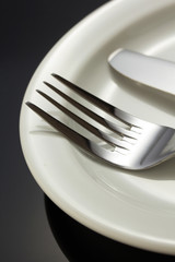 knife and fork at plate on black