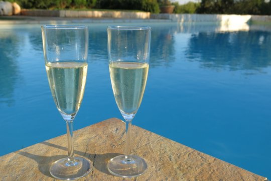 two champagne flutes by swimming pool
