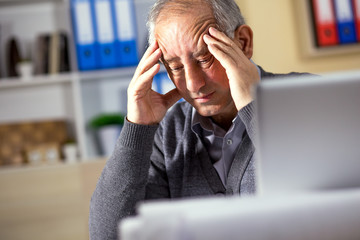 Portrait of exhausted senior businessman working in his office.