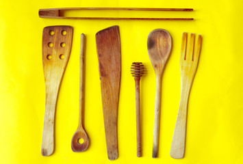 Old wooden spoons and stirrers on yellow background
