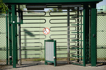 Dreheingang / Ein Dreheingang aus u-förmig gebogenen Metallrohren zu einem Industriegebiet.