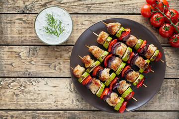 Turkey or chicken meat shish kebab skewers with tzatziki sauce and tomatoes on rustic wooden table...