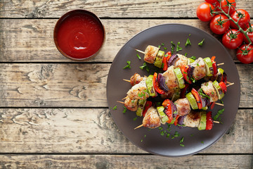Turkey or chicken meat shish kebab skewers with ketchup sauce, and tomatoes on rustic wooden table...