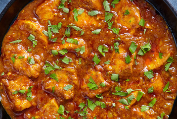 Chicken tikka masala close up texture, traditional spicy meat food with parsley