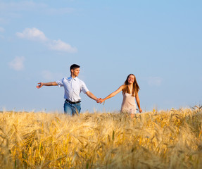 Young couple walking through  wheat field