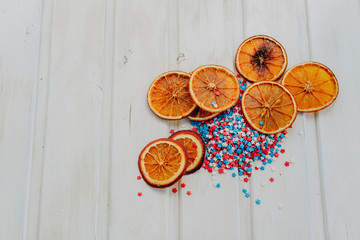 slices of dried oranges and star sprinkles on a white background with copyspace