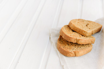 Fototapeta na wymiar Slices of toast rye bread on napkin on white wooden boards with copyspace