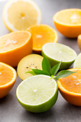 Mixed citrus fruit lemons, orange, kiwi, limes on a gray backgro