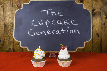 cupcakes on red in front of chalkboard written the cupcake generation on wood background