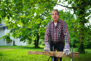Naklejka na ściany i meble Senior man sawing a log handsaw closeup