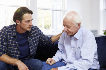 Adult Son Talking To Depressed Father At Home