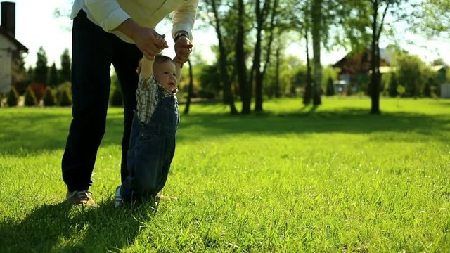 First steps son with father in yard in at the village
