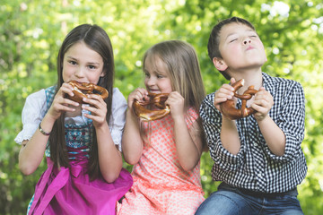 Drei Kinder beim Brezn essen im Freien