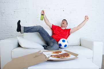 young football fan man watching game on tv in team jersey celebrating goal crazy happy on couch